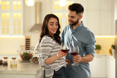 Photo of Lovely young couple drinking wine while cooking together at kitchen