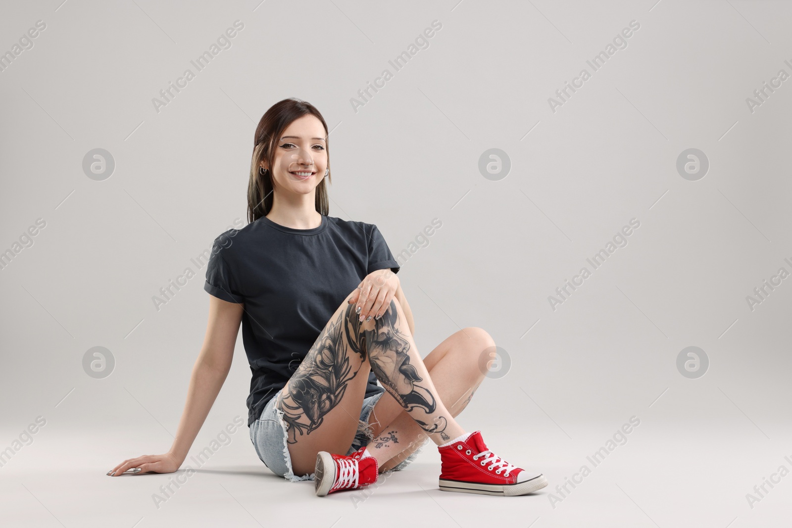 Photo of Smiling tattooed woman posing on grey background