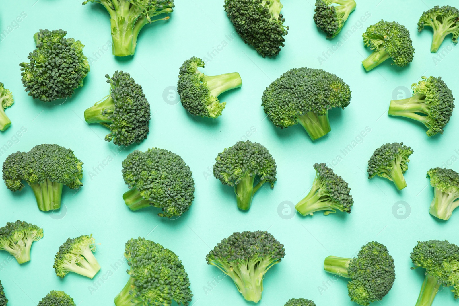 Photo of Fresh tasty broccoli on turquoise background, flat lay