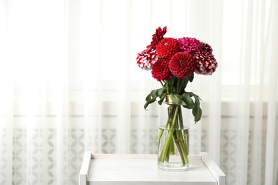 Photo of Beautiful dahlia flowers in vase indoors. Space for text