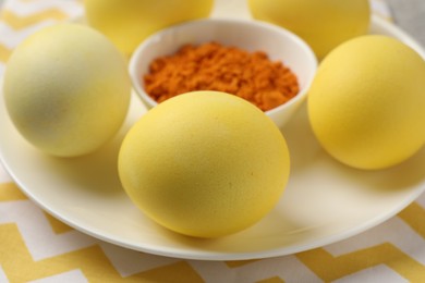 Photo of Yellow Easter eggs painted with natural dye and turmeric powder in bowl on table, closeup