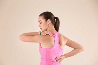 Photo of Woman in sportswear suffering from back pain on light background