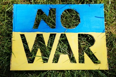 Photo of Poster in colors of Ukrainian flag with words No War on green grass, above view