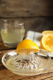 Photo of Squeezer with lemon and juice on wooden table