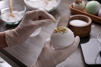 Photo of Woman in gloves making bath bomb at table, closeup