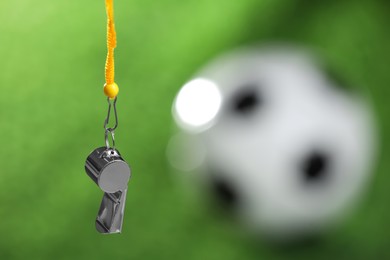 Photo of Football referee equipment. Metal whistle on blurred green background, closeup with space for text