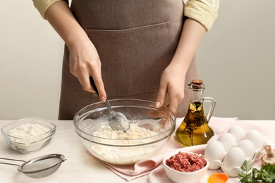 Photo of Woman making dough at white wooden table, closeup