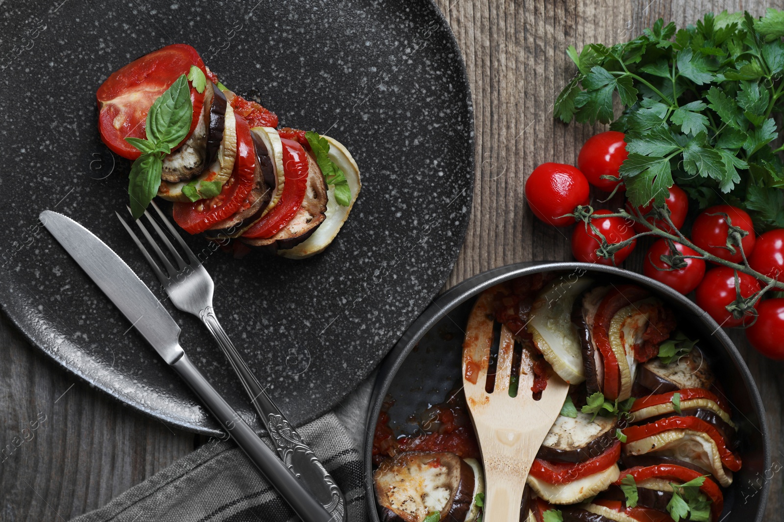 Photo of Delicious ratatouille served with basil on wooden table, flat lay