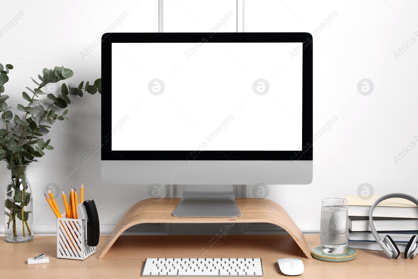 Photo of Cozy workspace with computer, headphones and stationery on wooden desk