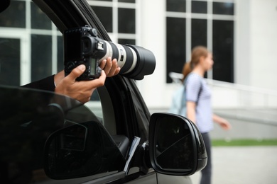 Private detective with camera spying from car, closeup