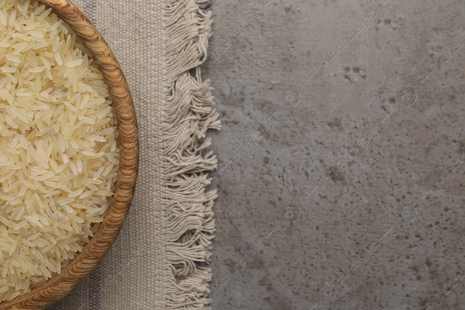 Photo of Bowl of raw rice on grey table, top view. Space for text