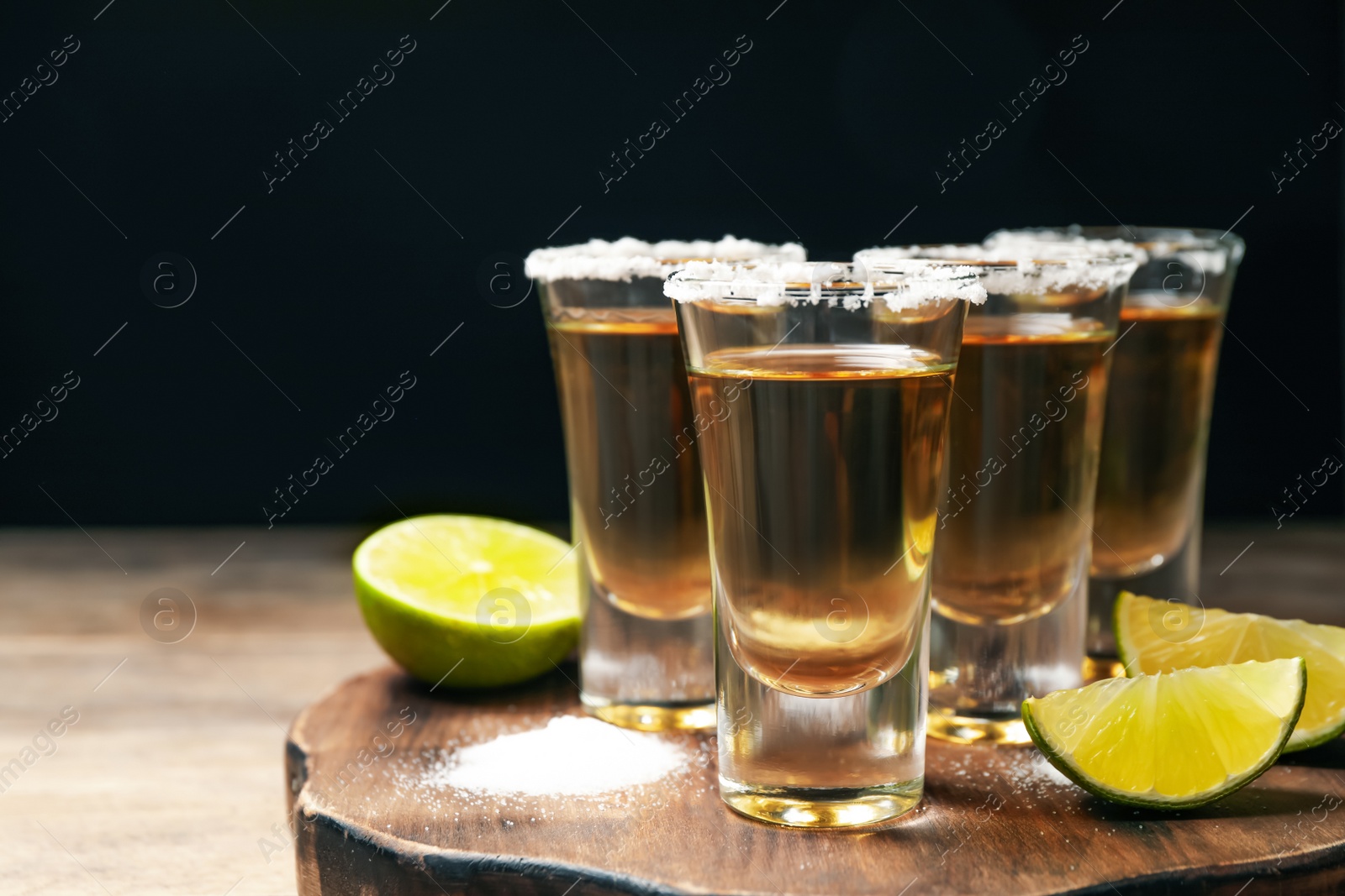 Photo of Mexican Tequila shots, lime and salt on wooden table