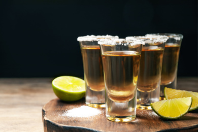 Photo of Mexican Tequila shots, lime and salt on wooden table