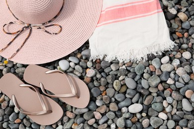 Beautiful hat and flip flops on pebbles, flat lay. Space for text