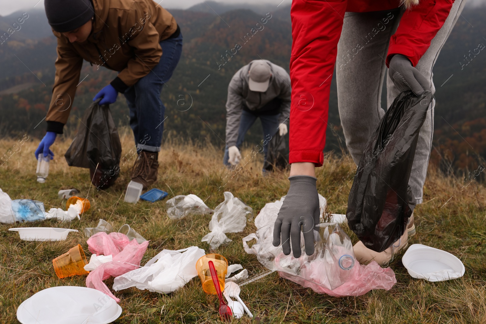 Photo of People with trash bags collecting garbage in nature, closeup