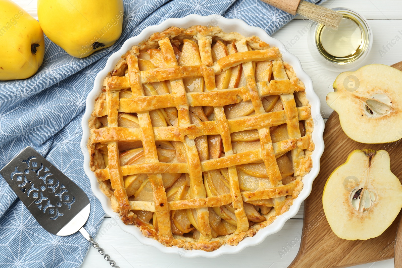 Photo of Tasty homemade quince pie, cake server and fresh fruits on white wooden table, flat lay