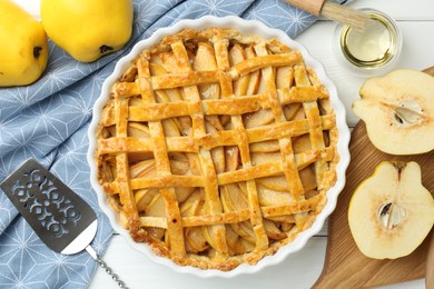 Tasty homemade quince pie, cake server and fresh fruits on white wooden table, flat lay