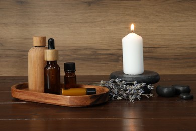 Photo of Aromatherapy products, burning candle and lavender on wooden table