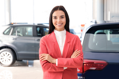 Happy young saleswoman in modern car salon