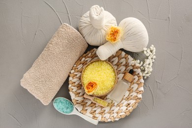 Photo of Sea salt, herbal bags, towel and roses on grey table, flat lay