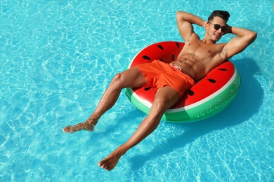 Photo of Young man with inflatable ring in pool on sunny day