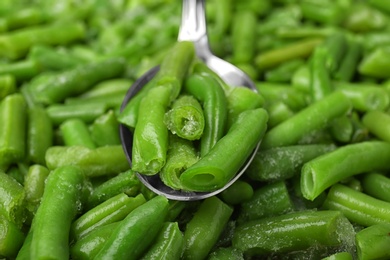 Photo of Spoon and frozen green beans, closeup. Vegetable preservation