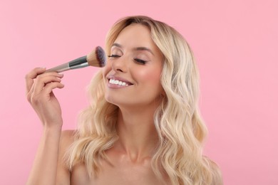 Photo of Beautiful makeup. Smiling woman with brush on pink background