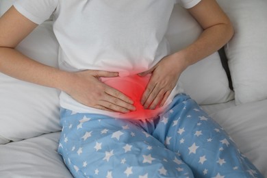 Woman suffering from abdominal pain on bed, closeup