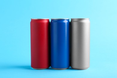 Photo of Energy drinks in colorful cans on light blue background