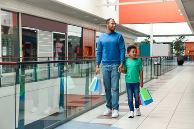 Photo of Family shopping. Happy father and son with colorful bags in mall