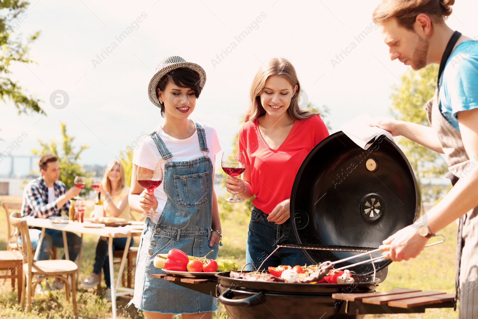 Photo of Young people having barbecue with modern grill outdoors