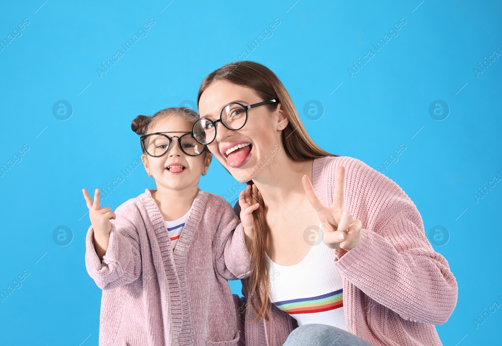 Photo of Young mother and little daughter with glasses on blue background