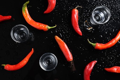 Photo of Flat lay composition with red hot chili peppers and vodka on black table