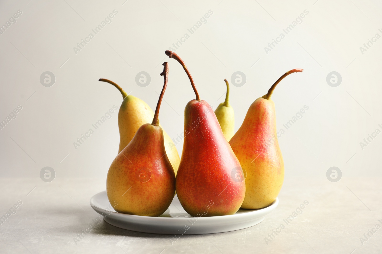 Photo of Plate with ripe pears on light background