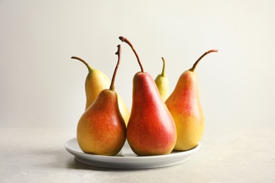 Plate with ripe pears on light background