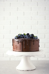 Fresh delicious homemade chocolate cake with berries on table against brick wall