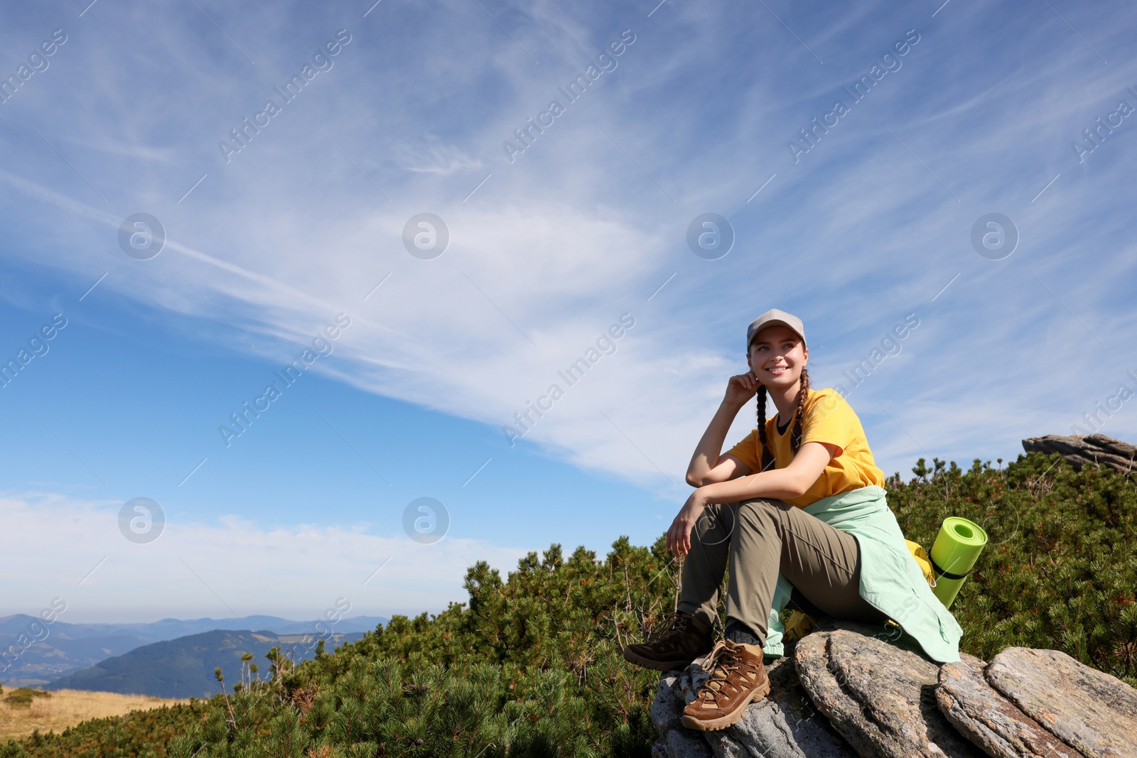 Photo of Tourist with backpack on cliff in mountains. Space for text