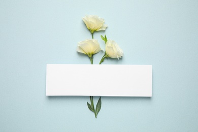 Photo of Beautiful white Eustoma flowers and card with space for text on light background, flat lay