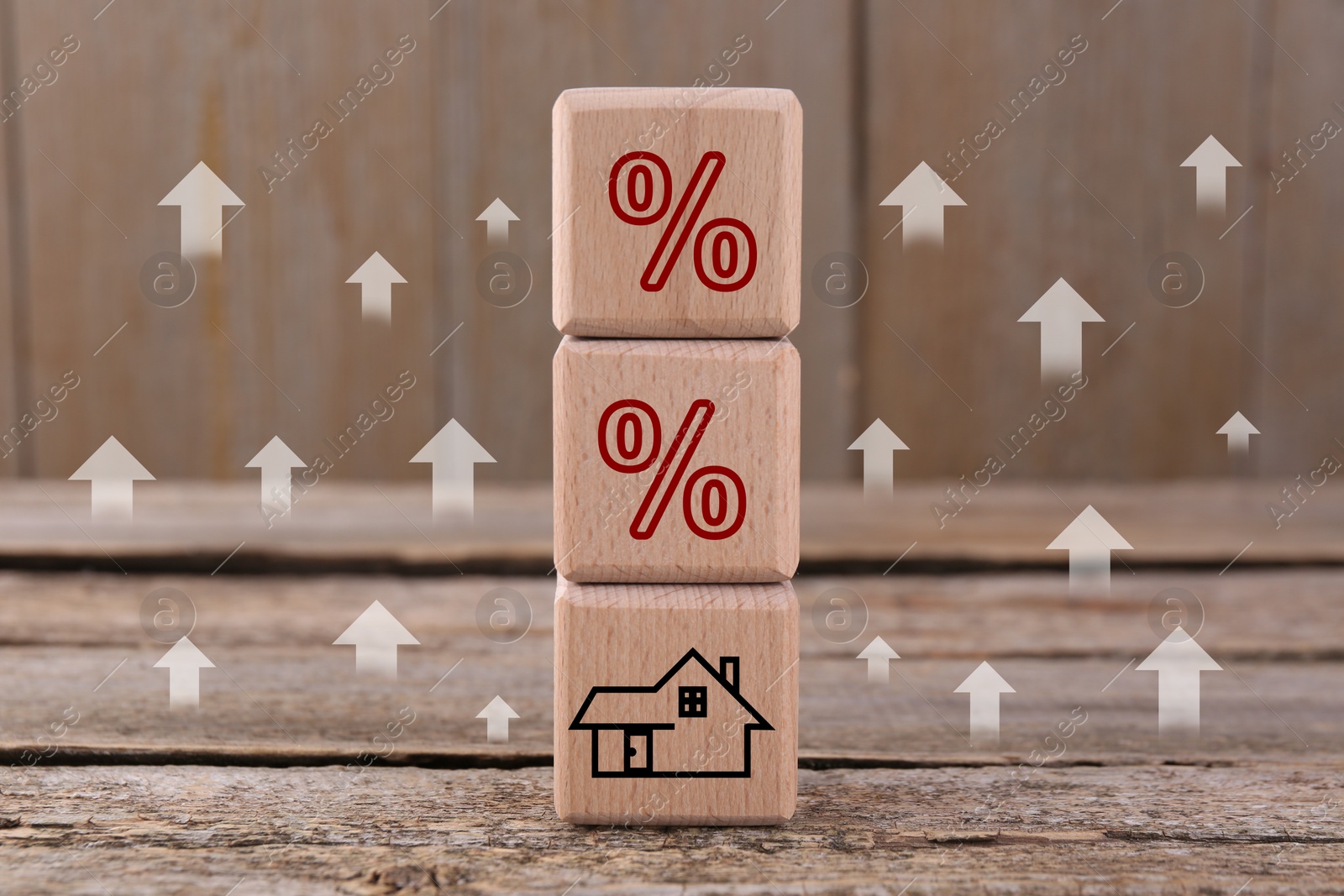 Image of Mortgage rate rising illustrated by upward arrows and percent signs. Cubes with house icon on wooden table