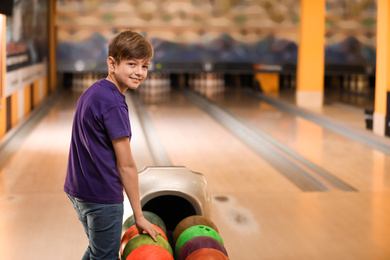 Photo of Preteen boy near balls in bowling club. Space for text