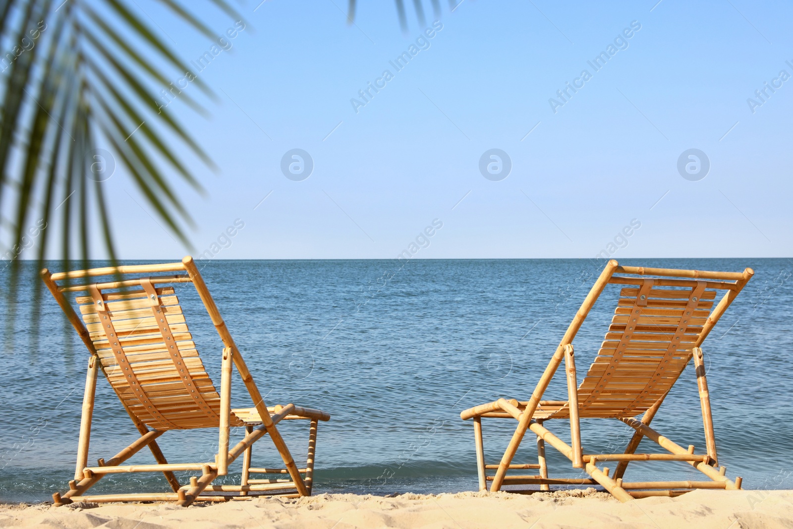 Photo of Sandy beach with empty wooden sunbeds on sunny day