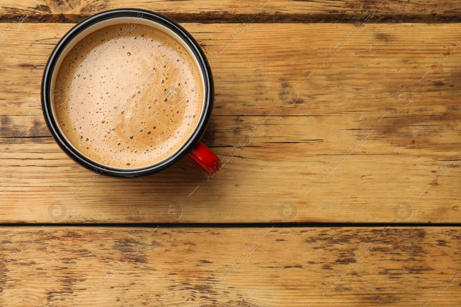 Photo of Cup of aromatic coffee on wooden table, top view. Space for text