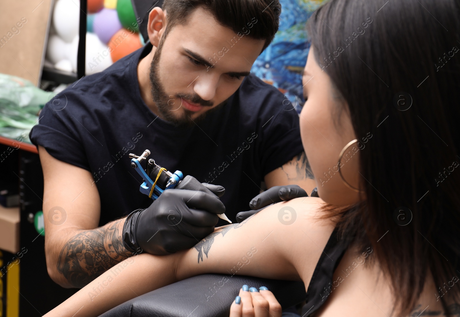 Photo of Professional artist making tattoo with machine in salon