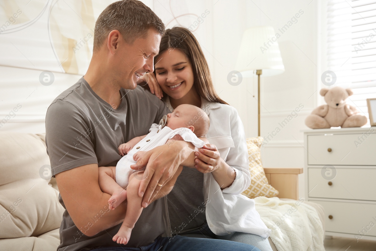 Photo of Happy couple holding their sleeping baby at home