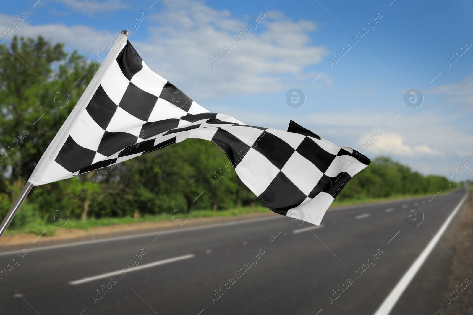 Image of Checkered racing finish flag and asphalt road outdoors