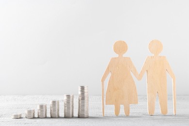 Pension savings. Figure of senior couple and stacked coins on grey wooden table