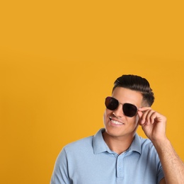 Photo of Handsome man wearing sunglasses on yellow background