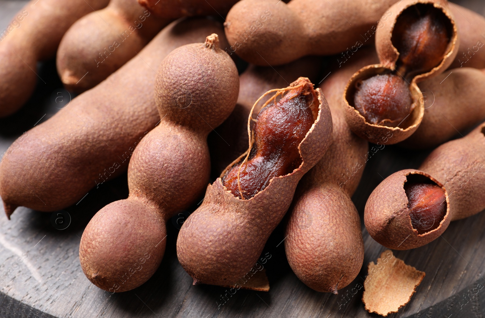 Photo of Delicious ripe tamarinds on wooden board, closeup