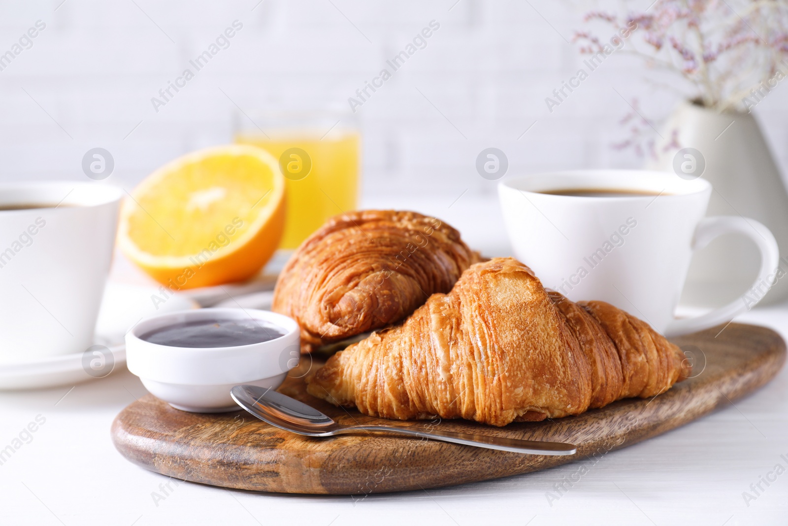 Photo of Tasty breakfast. Cup of coffee, jam and croissants on white wooden table