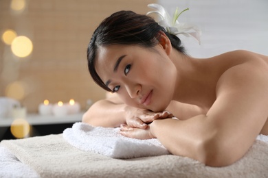 Beautiful Asian woman lying on massage table in spa salon